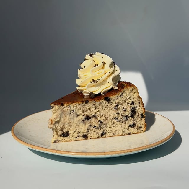 Cheesecake slice with a cream rosette on a ceramic plate